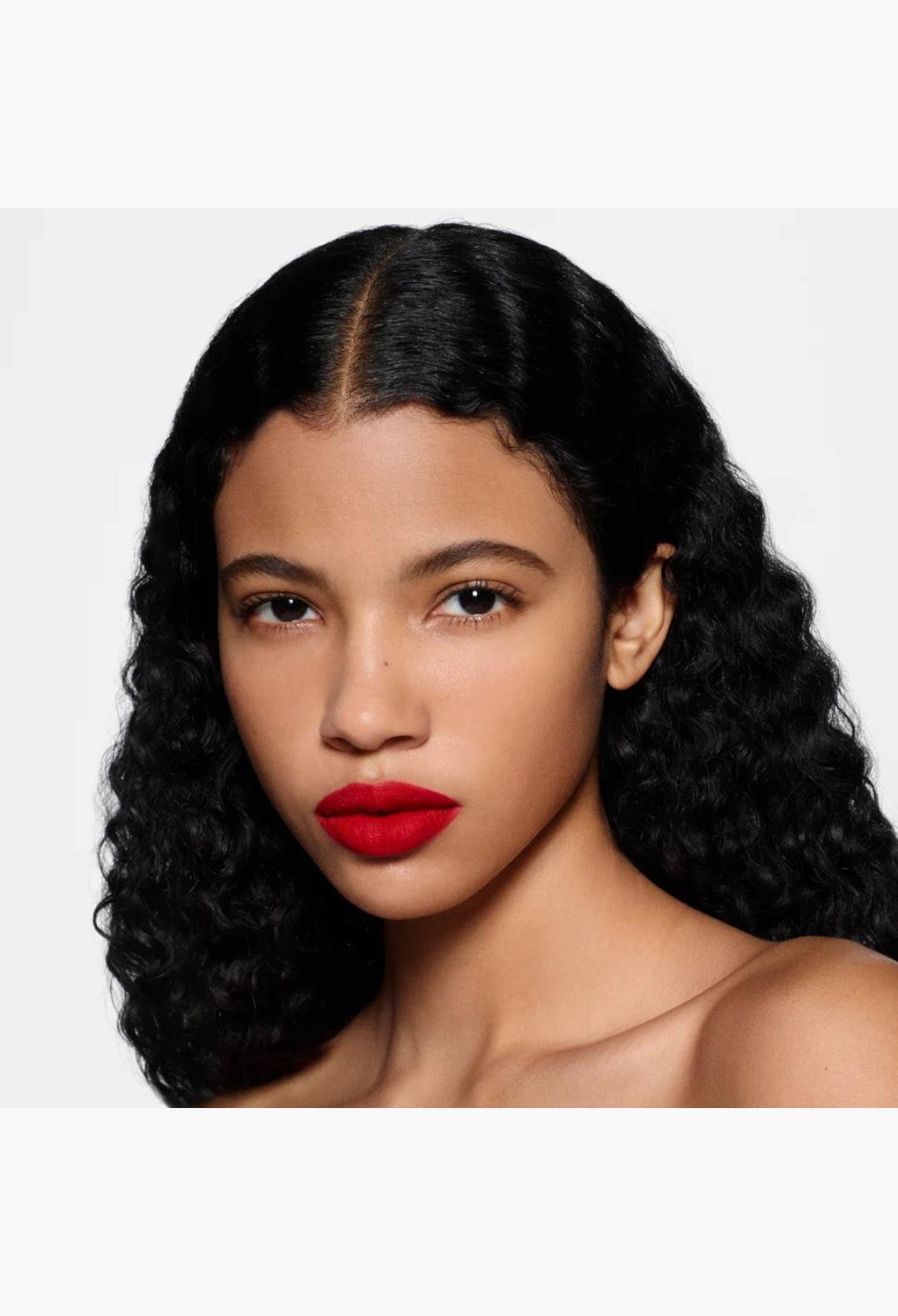 GLAM MODA Rouge Victoria matte red lipstick on a model with long dark wavy hair, showcasing a bold demi-matte finish.