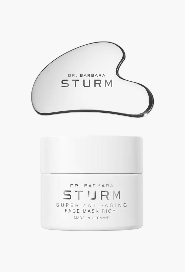 GLAM MODA Dr. Barbara Sturm Super Anti-Aging Face Mask Rich jar and silver gua sha tool on a white background.