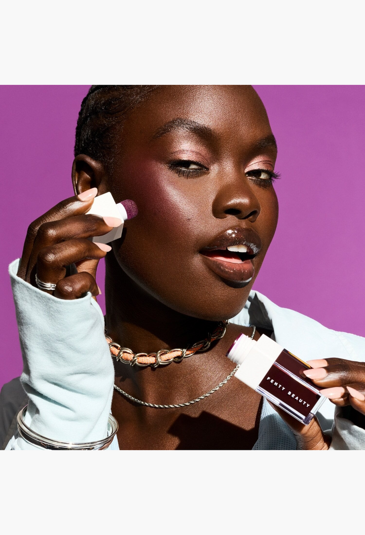 GLAM MODA model applying deep berry liquid blush with a squish-tip sponge applicator on a vibrant purple background