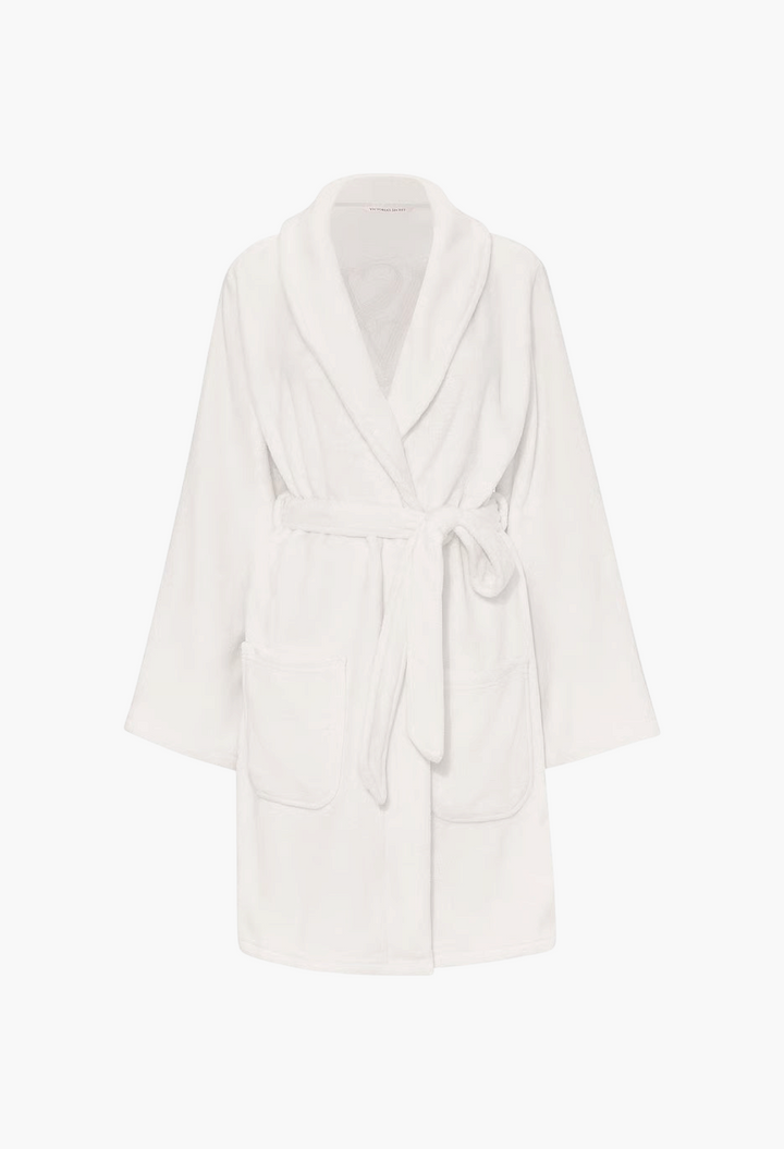 GLAM MODA white plush robe with a shawl collar, tie waist belt, and side pockets in soft polyester fabric.