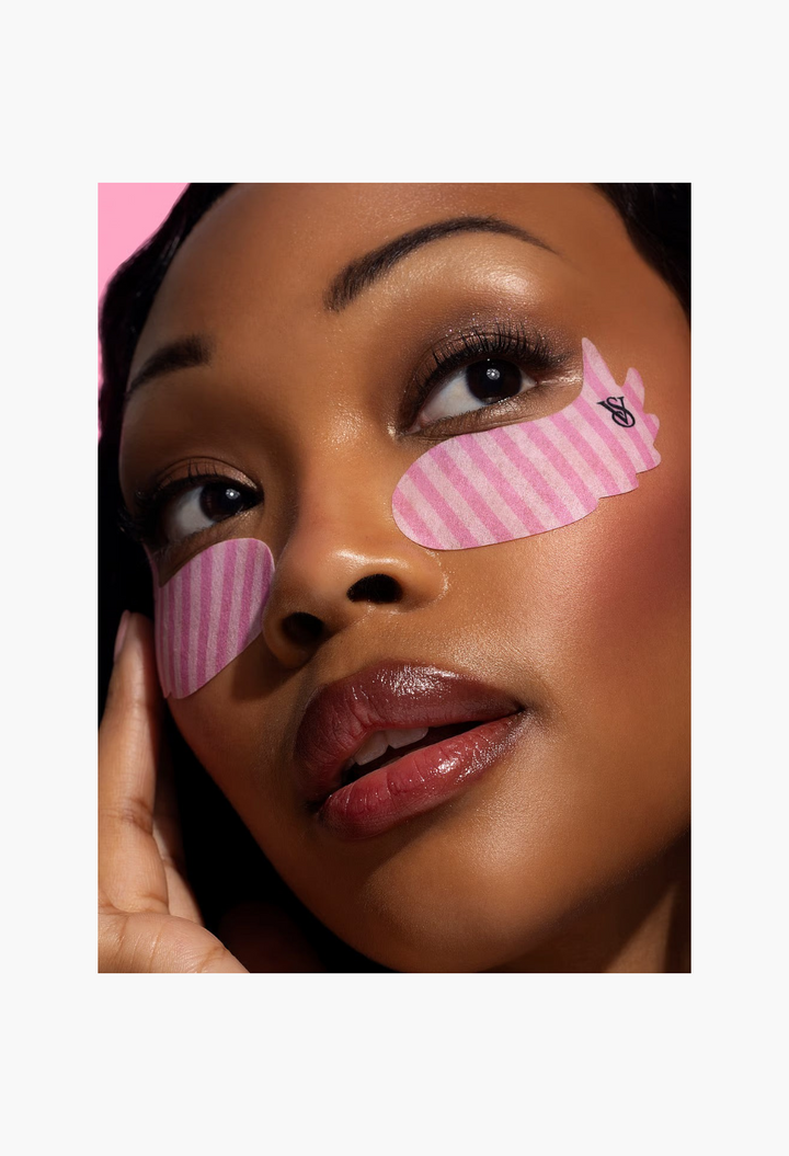 GLAM MODA model wearing pink striped Victoria's Secret x Patchology wing-shaped hydrating undereye patches