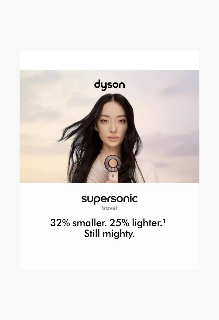 GLAM MODA model holding a compact Dyson Supersonic travel hair dryer in ceramic pink with a styling concentrator.