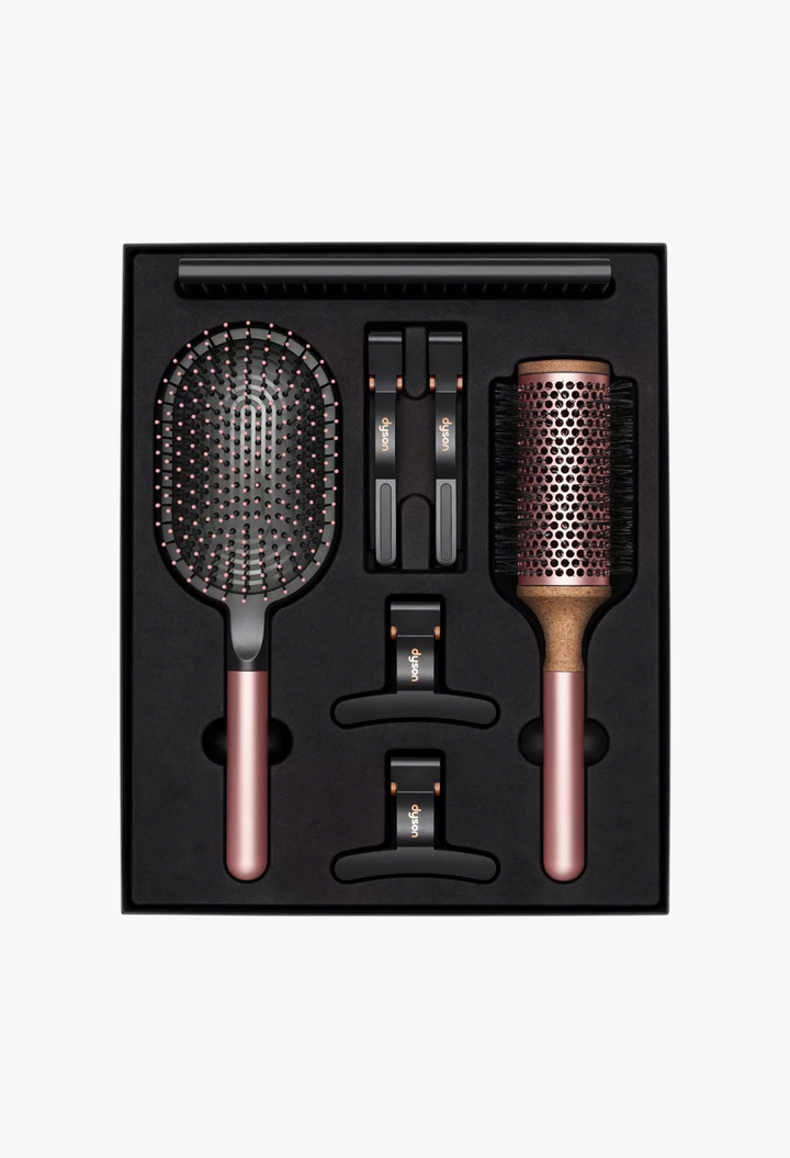GLAM MODA Dyson Styling Gift Set featuring a paddle brush, vented barrel brush, detangling comb, and four hair clips.
