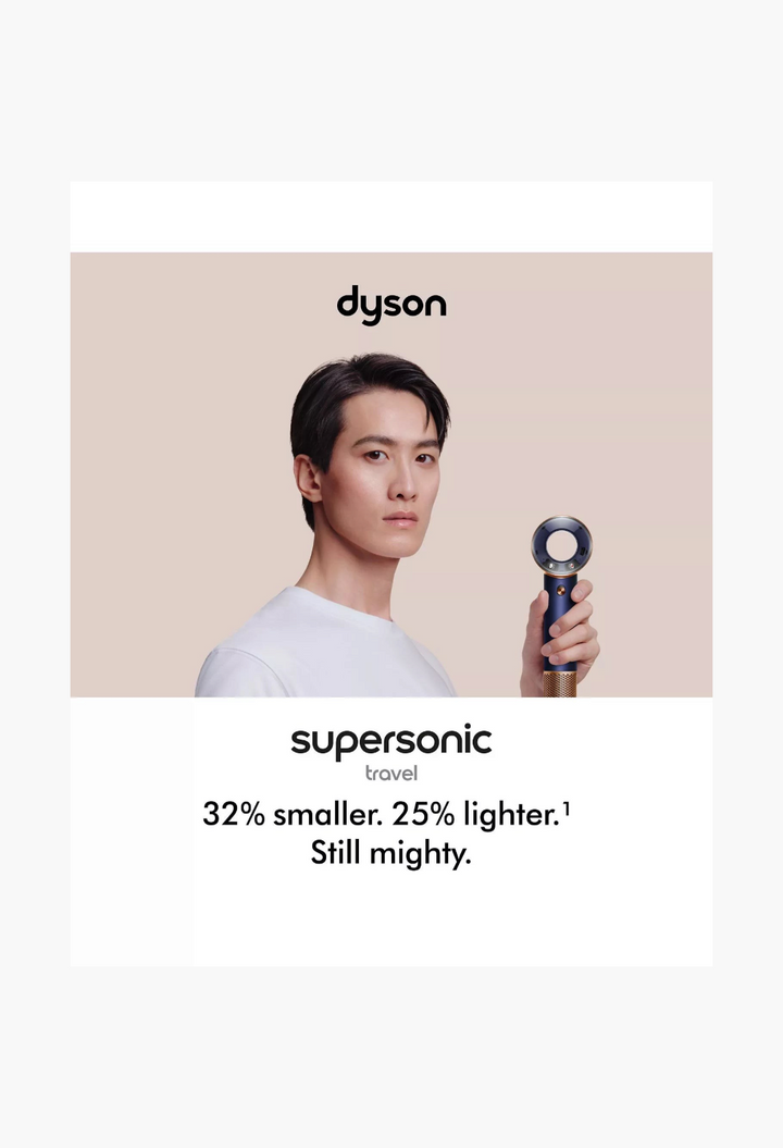GLAM MODA model holding a Prussian Blue and Copper Dyson Supersonic Travel hair dryer against a neutral background
