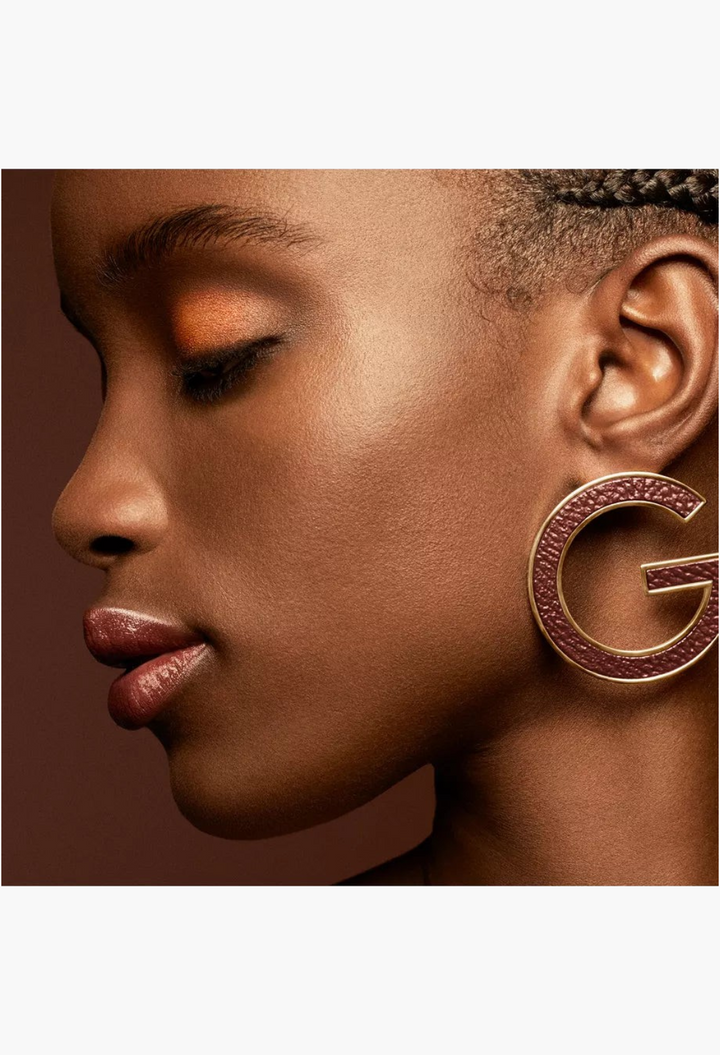 GLAM MODA Ombres G Eyeshadow Quad in Undressed Brown applied on a model with warm skin tone and gold G-logo earring