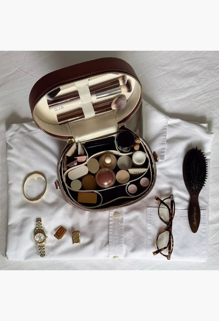 GLAM MODA oval vegan leather toiletry case in dark brown, open and filled with makeup brushes and cosmetics.