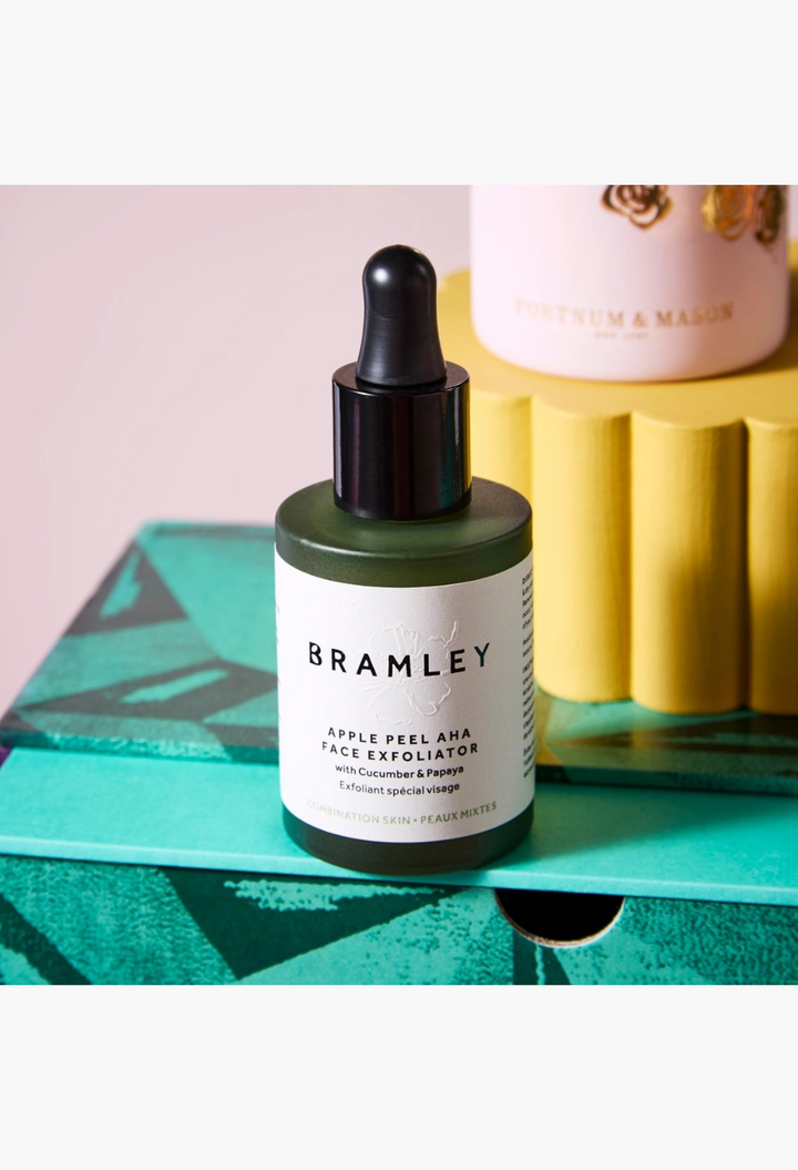 GLAM MODA Bramley Apple Peel AHA Face Exfoliator in a dark green bottle with a dropper cap, displayed on a patterned box.
