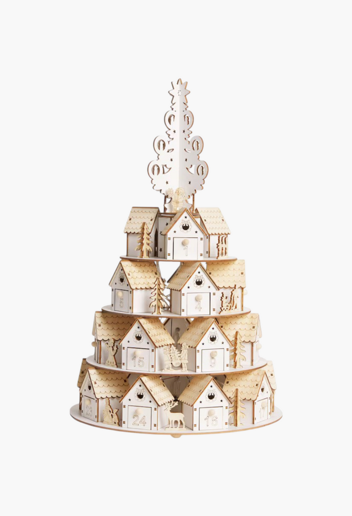 GLAM MODA tiered 3D wooden advent calendar featuring miniature houses and a Christmas tree topper on a white background
