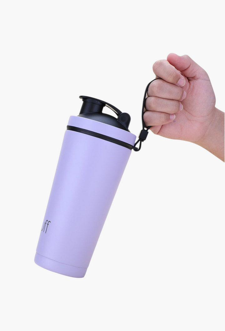 GLAM MODA light purple stainless steel insulated shaker bottle with a black lid and carry strap held by a hand