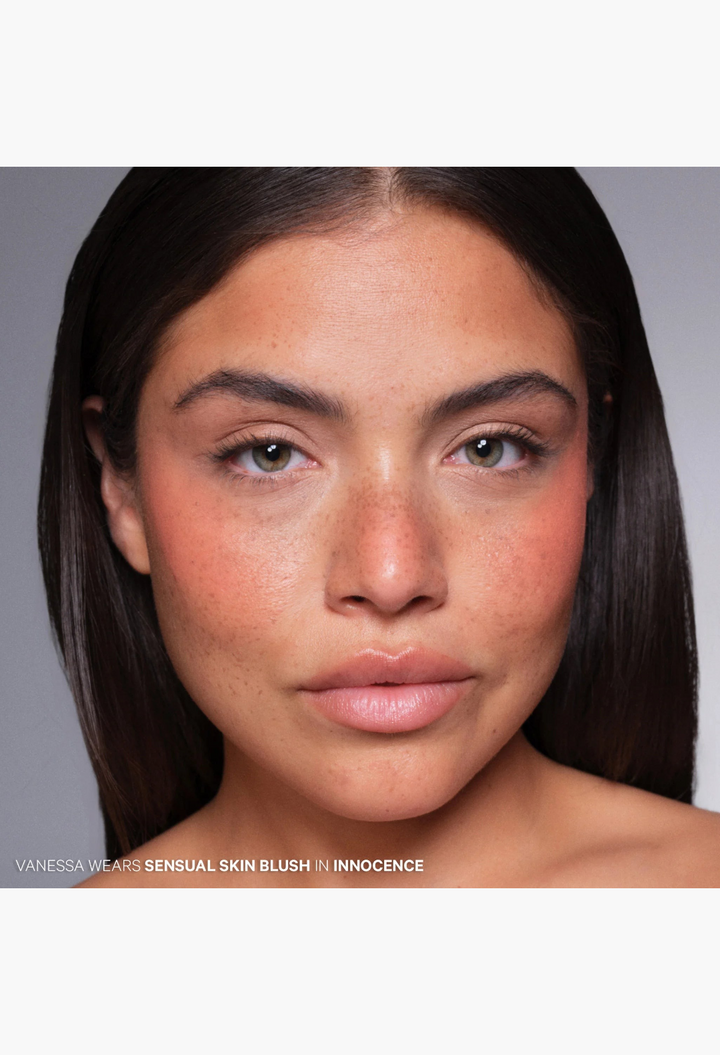 Model wearing GLAM MODA Sensual Skin Blush in Innocence, an apricot cream-to-powder formula for a soft-focus finish.