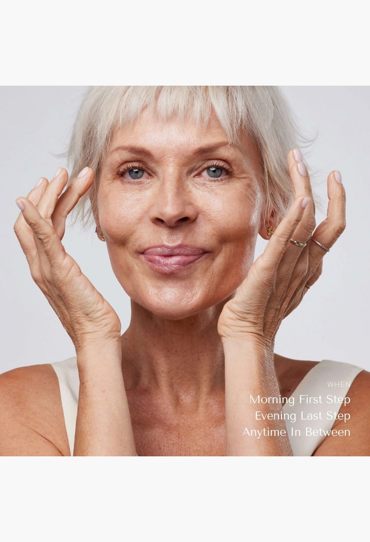 GLAM MODA mature woman with short silver hair applying solid serum to her face for radiant and nourished skin