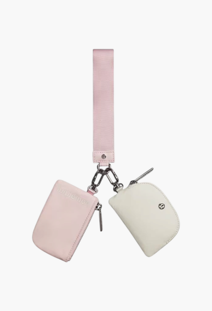 GLAM MODA dual pouch wristlet featuring a pink fabric strap with one light pink and one white zippered pouch.