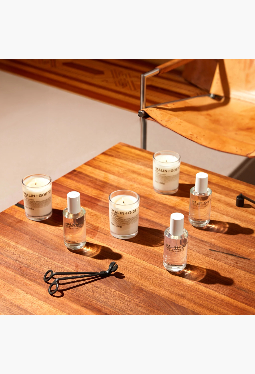 GLAM MODA collection of Malin + Goetz tomato home sprays and candles with a black metal wick trimmer on white background