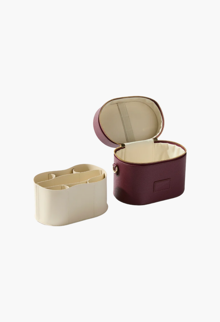 GLAM MODA oval vegan leather toiletry case in deep burgundy with a removable cream-colored internal divider insert.