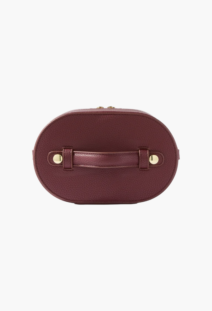 GLAM MODA oval toiletry case in deep burgundy vegan leather with a top handle and gold hardware details.