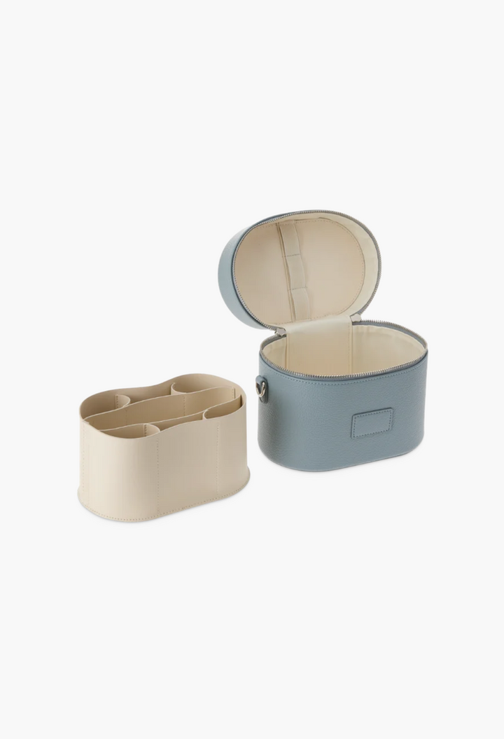 GLAM MODA oval toiletry case in blue vegan leather with a removable cream divider insert and brush storage.