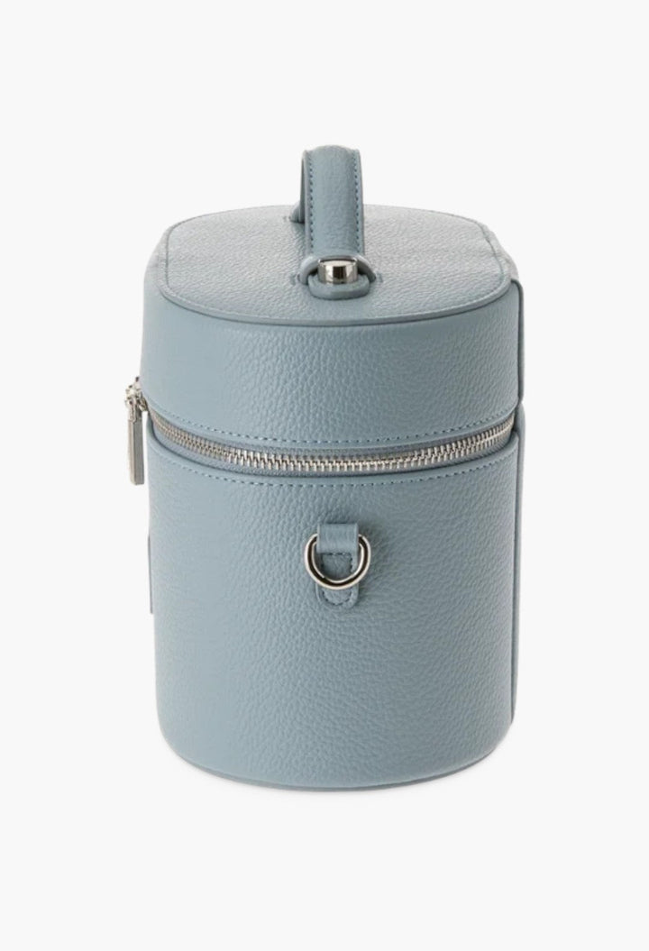 GLAM MODA oval toiletry case in light blue vegan leather with a top handle, silver hardware, and shoulder strap rings.