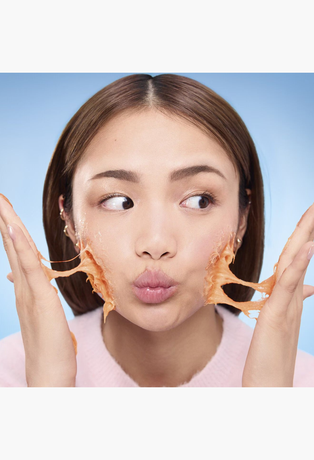 GLAM MODA model applying orange mochi-textured brightening cleanser with Vitamin C to her face