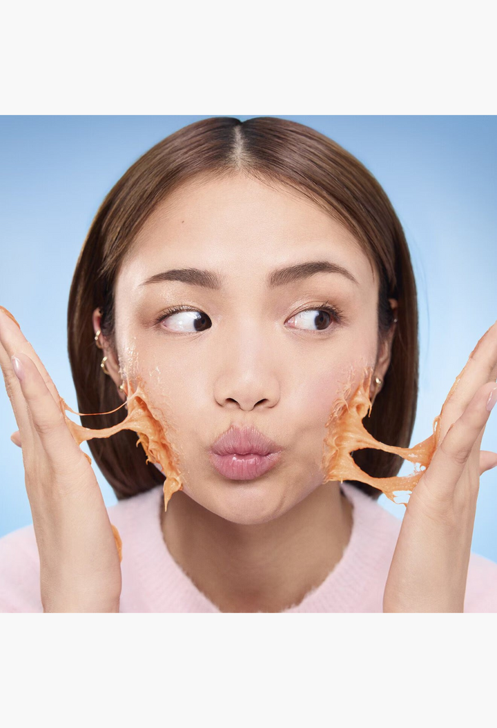 GLAM MODA model applying orange mochi-textured brightening cleanser with Vitamin C to her face