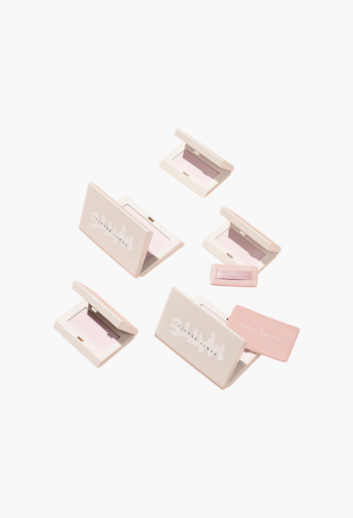 GLAM MODA Fenty Beauty Invisimatte mini setting powder compacts and sponges arranged on a soft peach background.
