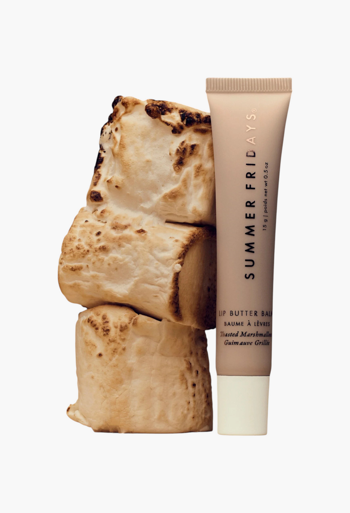 GLAM MODA Summer Fridays Toasted Marshmallow lip butter balm tube next to a stack of toasted marshmallows.