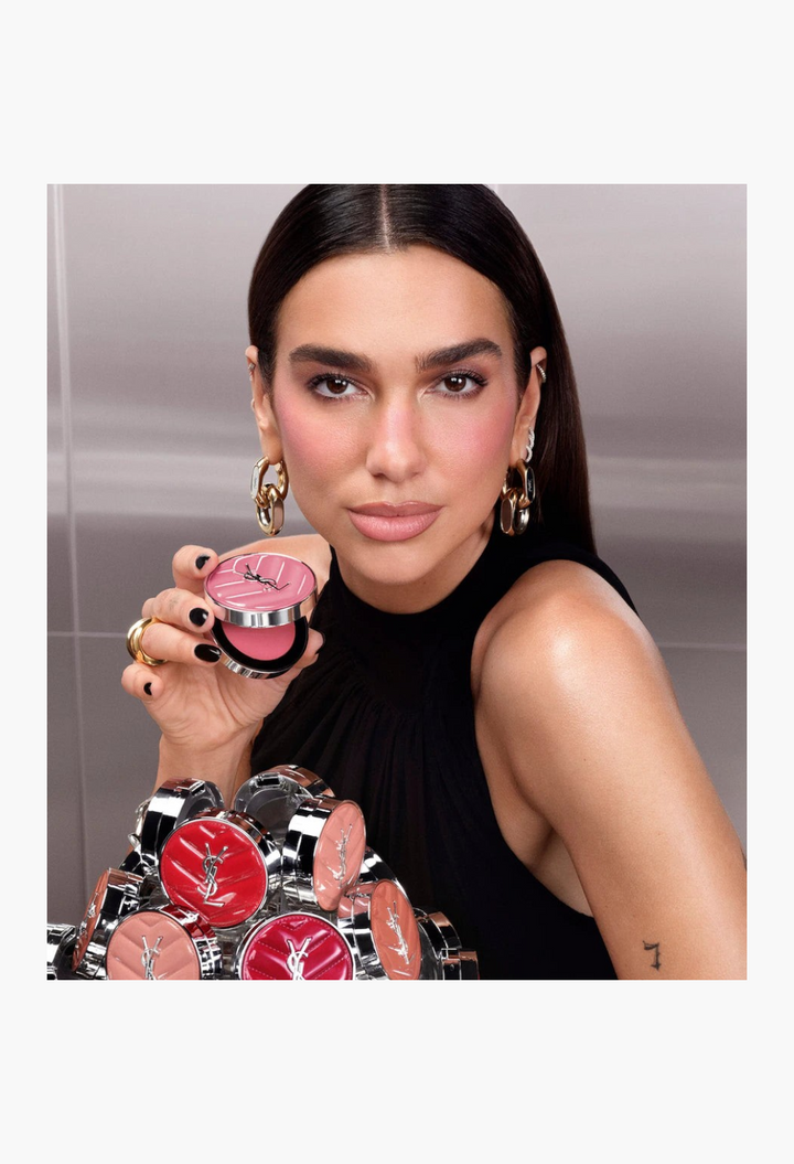 GLAM MODA model holding a pink YSL Make Me Blush cream blush compact with a dewy finish and vibrant pigment.