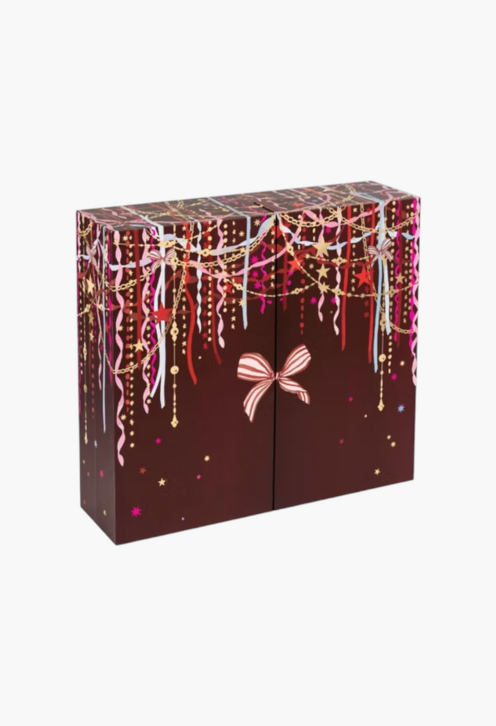 GLAM MODA 24 Days of Luxe Beauty Advent Calendar in deep brown with festive gold, pink, and white ribbon decorations.