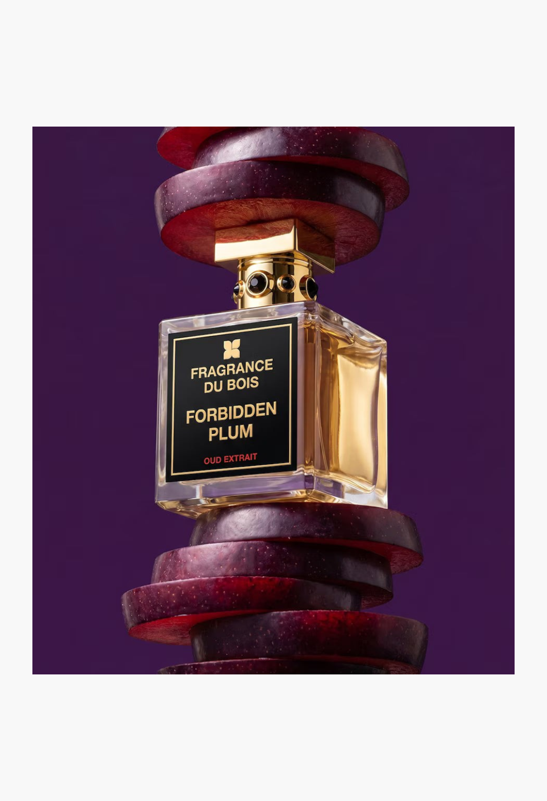 GLAM MODA Fragrance Du Bois Forbidden Plum Oud Extrait perfume bottle surrounded by fresh sliced purple plums
