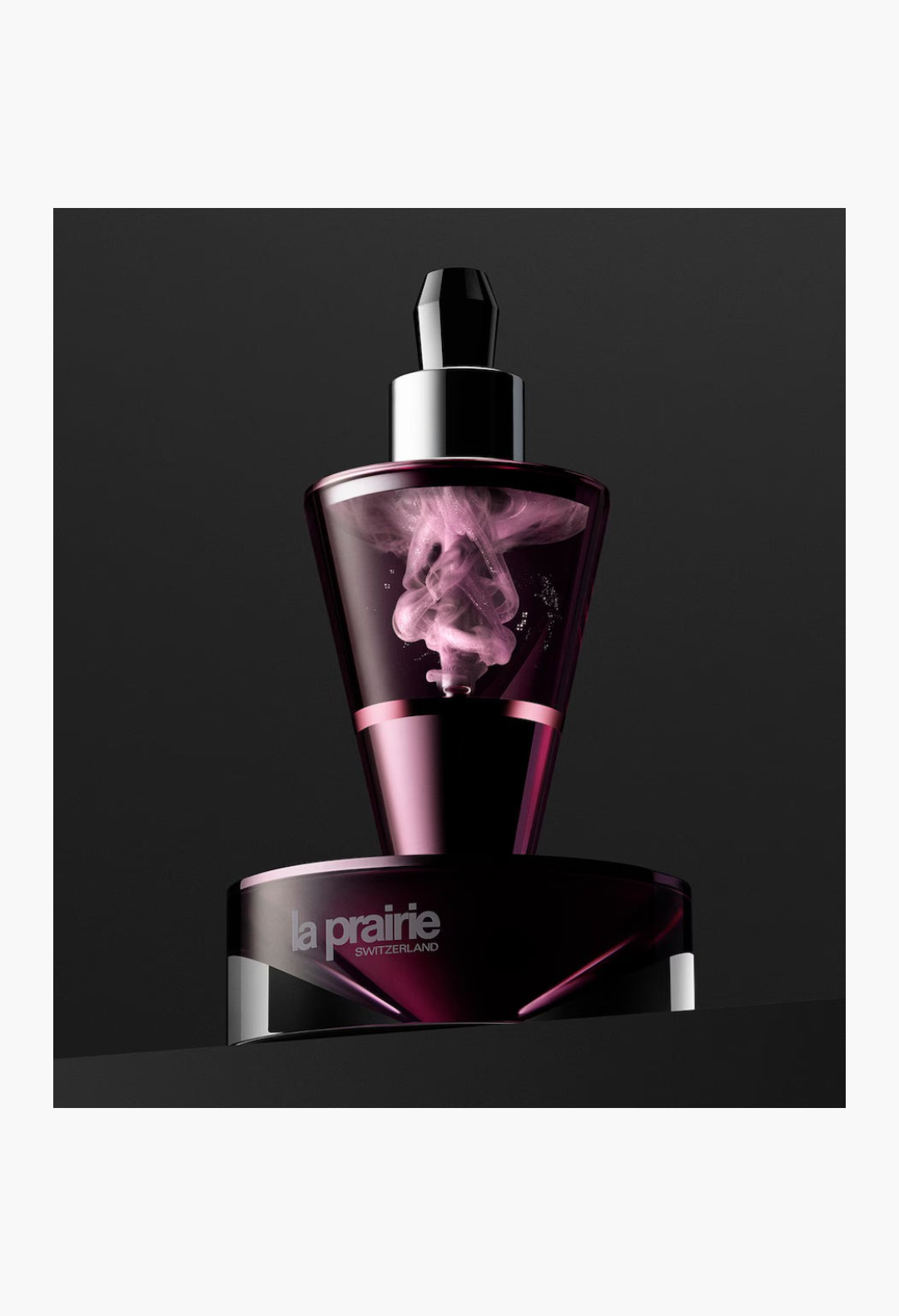 GLAM MODA La Prairie Platinum Rare Haute-Rejuvenation Protocol serum vial with swirling pink formula in dark glass
