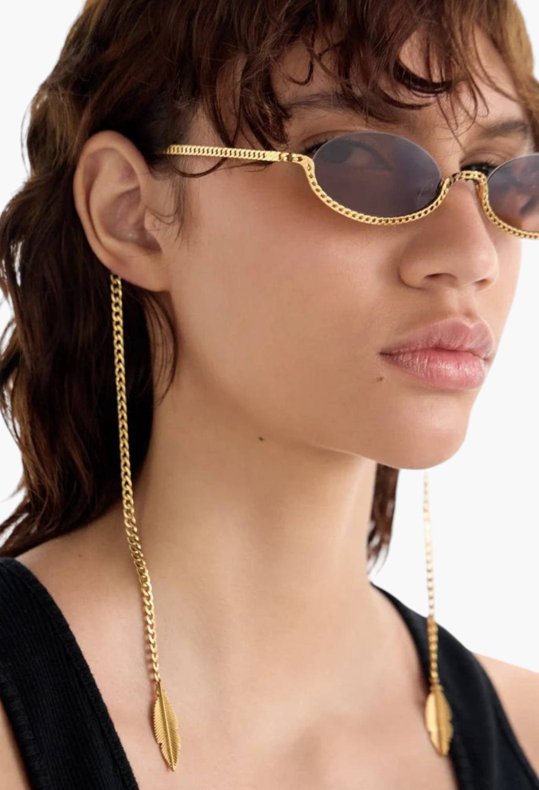 Model wearing GLAM MODA Gaga gold metal sunglasses with sculptural chain frames and hanging feather charms