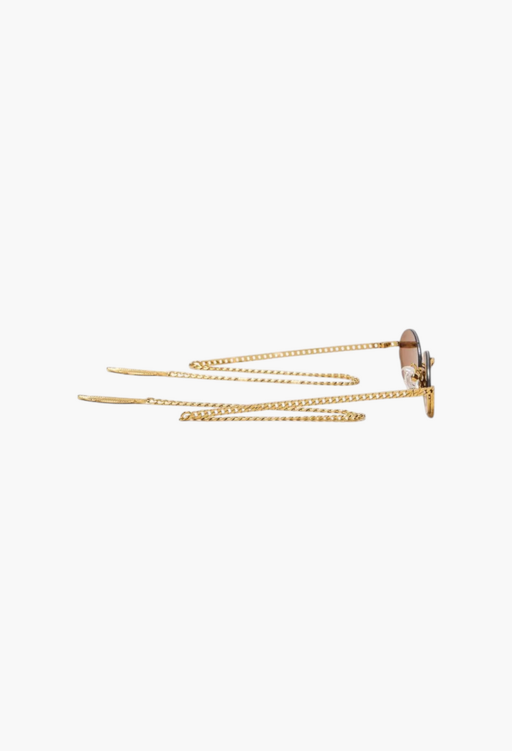 GLAM MODA Gaga sunglasses in gold metal with sculptural frames and an integrated decorative gold chain accessory.