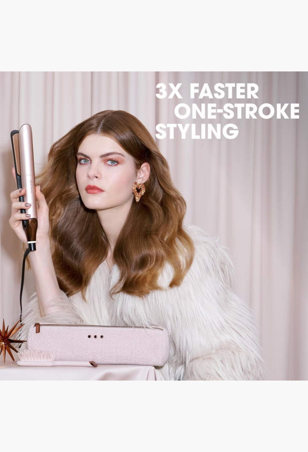 GLAM MODA model holding a rose gold ghd Chronos hair styler with a matching paddle brush and storage bag on a table