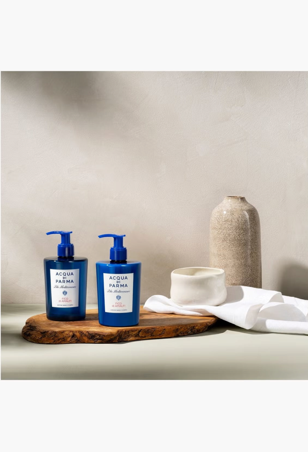GLAM MODA Acqua Di Parma Fico di Amalfi hand and body wash bottles on a wooden board with decorative ceramic vases.
