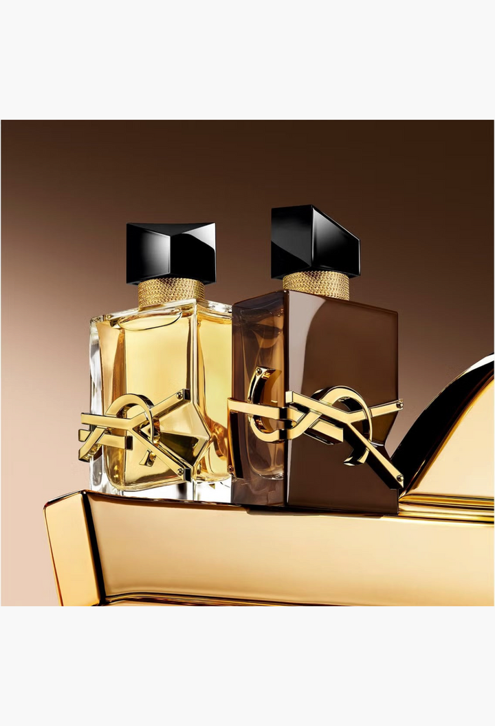 GLAM MODA YSL Libre Santal Couture and classic Libre perfume bottles with gold logo accents on a gold surface