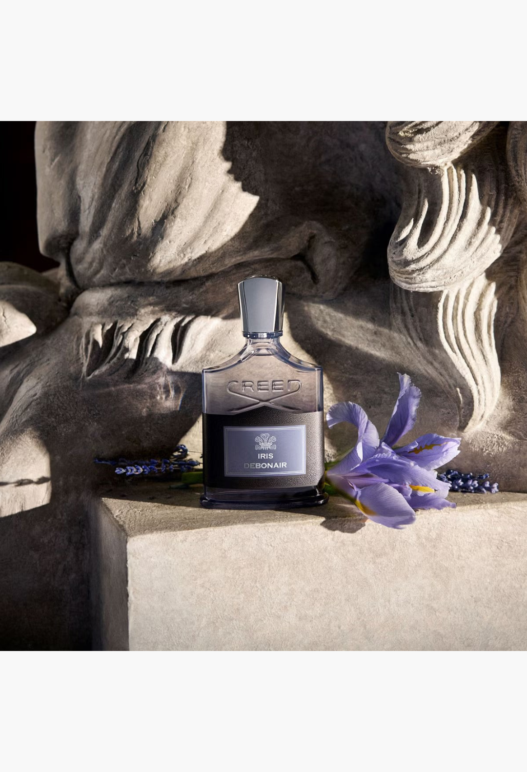 GLAM MODA Creed Iris Debonair Eau De Parfum in a glass bottle with a purple iris flower on a white background.