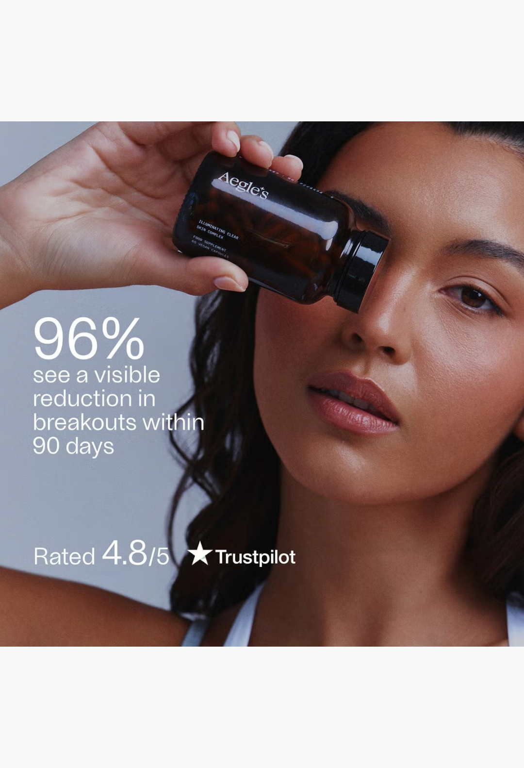 GLAM MODA model holding a brown glass bottle of Aegle Clear Skin Complex supplement near her face