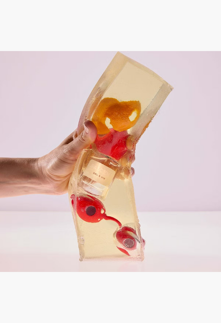 GLAM MODA Fascent Sel À Vie perfume bottle encased in a textured golden resin block with orange peel and red berries