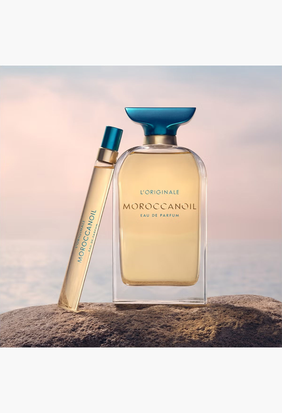 GLAM MODA Moroccanoil L'Originale Eau de Parfum bottle and travel spray featuring amber fragrance and teal cap