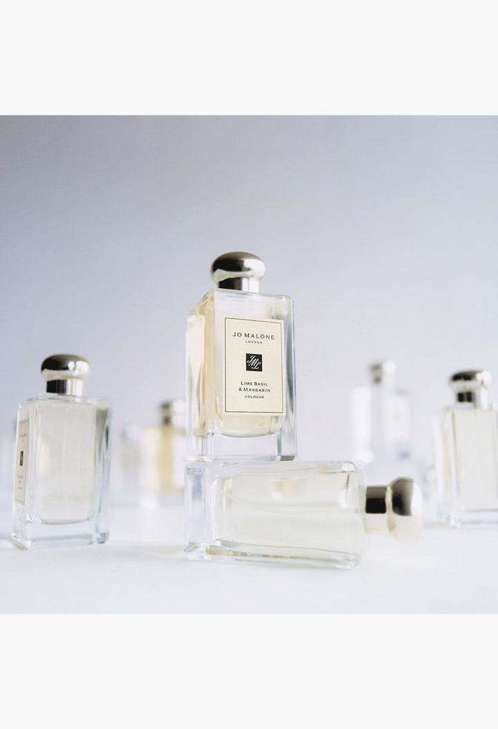 GLAM MODA Grapefruit Cologne glass perfume bottles with silver caps arranged in a minimalist studio setting.