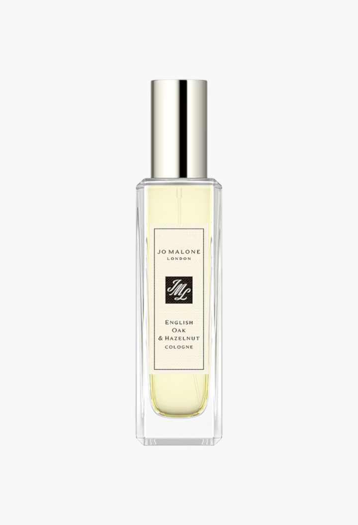GLAM MODA Jo Malone London English Oak & Hazelnut cologne in a clear glass spray bottle with a silver cap.