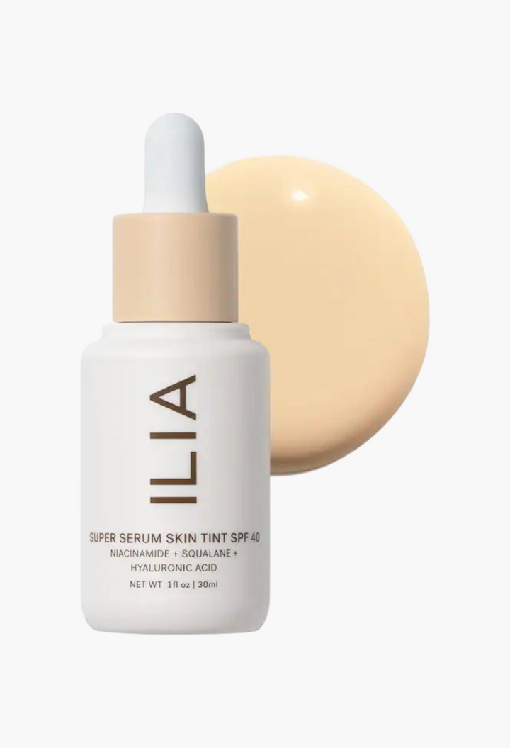 GLAM MODA ILIA Super Serum Skin Tint SPF 40 bottle with a swatch of light liquid foundation on a white background.