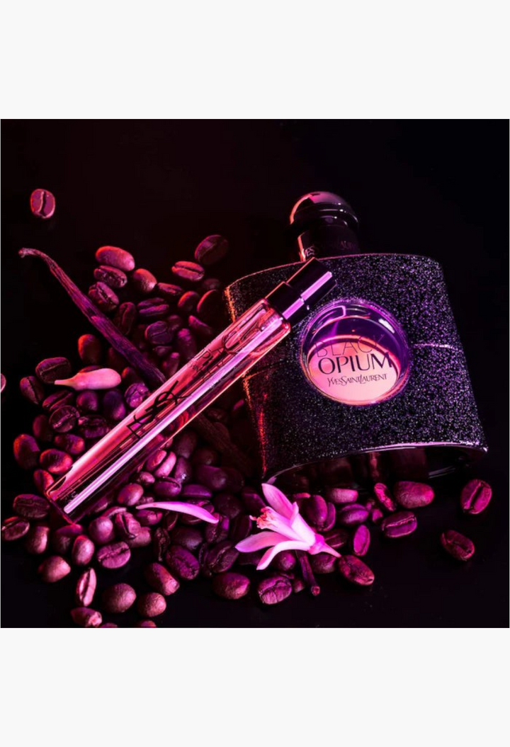 GLAM MODA Black Opium perfume set with coffee beans, vanilla pods, and white flowers on a dark background