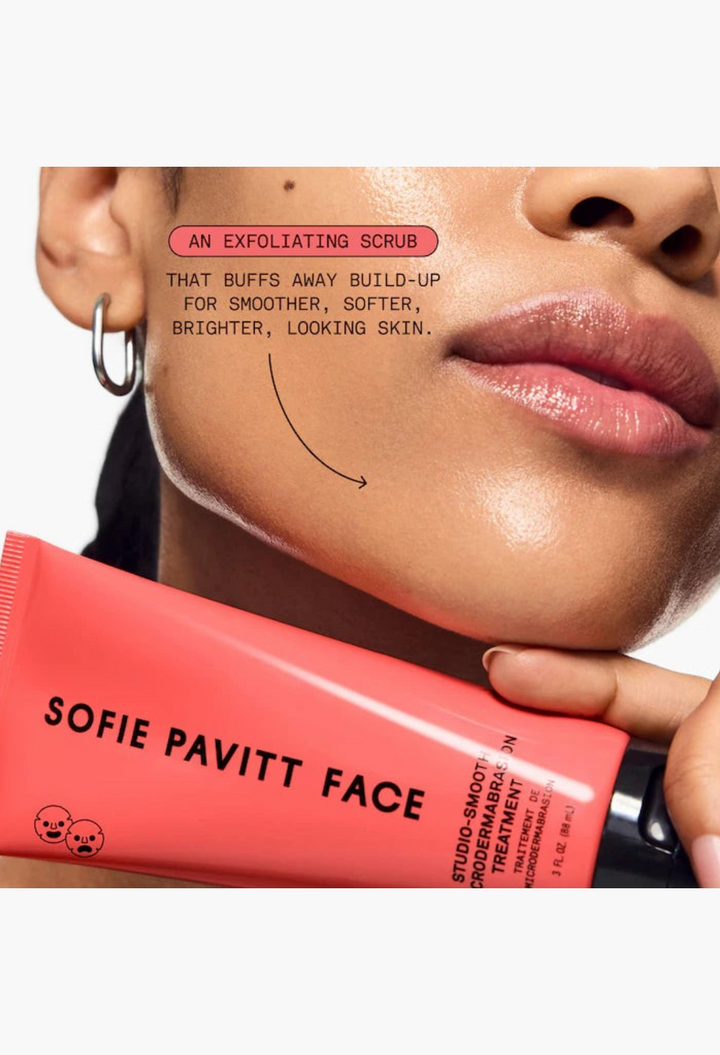 GLAM MODA Studio-Smooth microdermabrasion exfoliating scrub tube held against a model's glowing, smooth cheek.