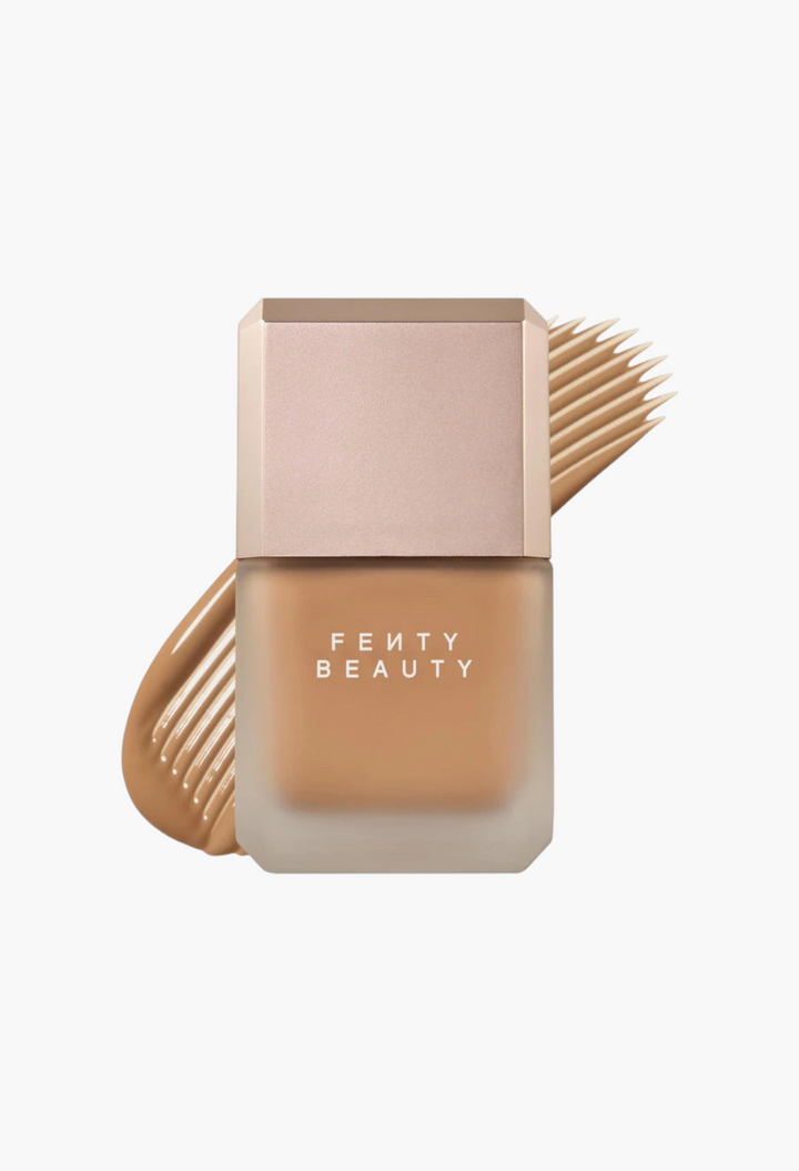 GLAM MODA Fenty Beauty Pro Filt'r liquid foundation in a frosted glass bottle with a swatch of tan makeup behind it.