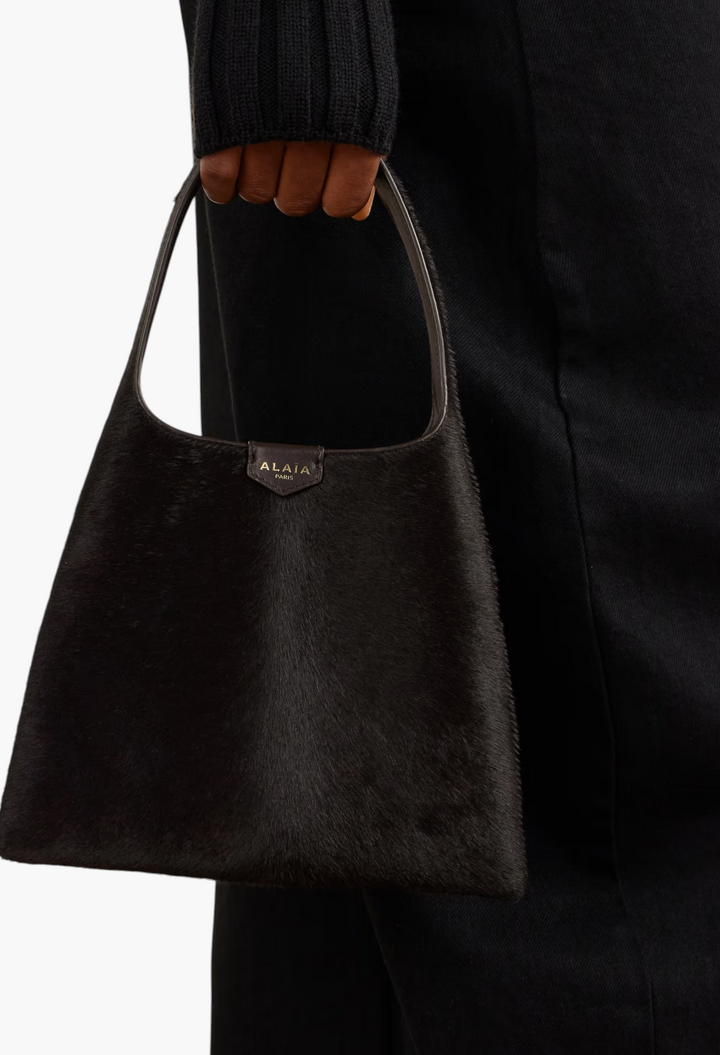 GLAM MODA Alaïa mini shoulder bag in dark brown calf hair with a slouchy silhouette and leather shoulder strap.